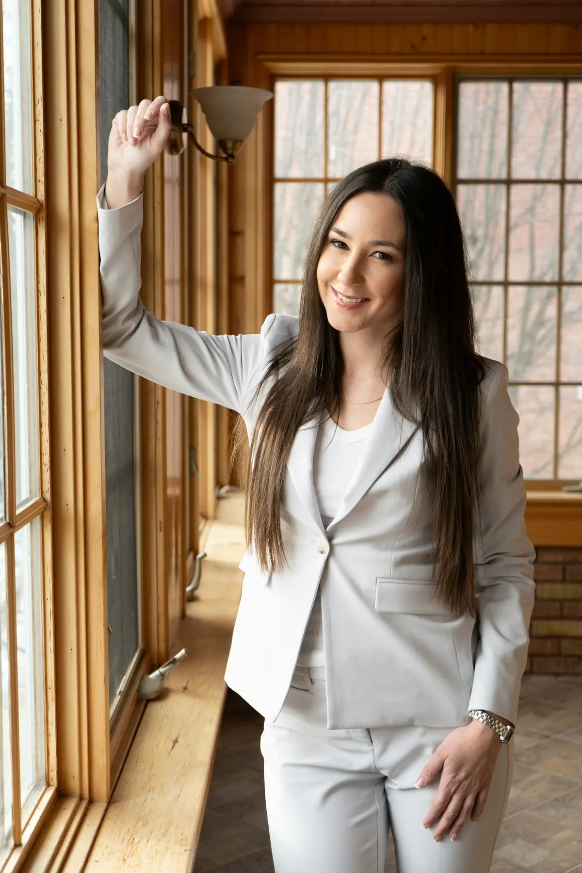 Nell Ostrander smiling by a tall wooden window